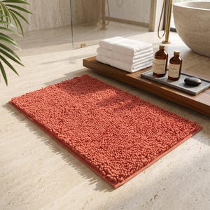 May include: A rectangular bath mat with a deep terracotta orange colour and a thick, shaggy, textured pile surface. The mat features a dense, tufted construction with a consistent loop pattern across the entire top surface and a finished edge.