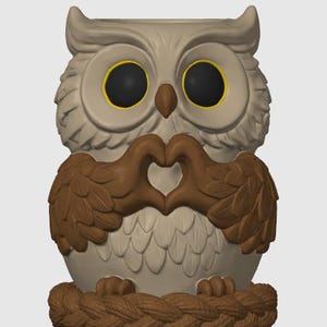 May include: A beige and brown owl figurine featuring large black eyes with yellow rings, a brown beak, and wings positioned to form a heart shape in front of its chest. The owl is perched on a circular base with a textured, braided rope design.
