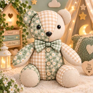 May include: A plush teddy bear featuring a patchwork design of sage green fabric with a white daisy floral pattern and a beige and white gingham check pattern. The bear has a matching gingham bowtie, three wooden buttons, and black eyes.