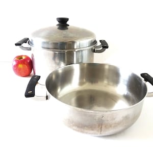 May include: Two stainless steel pots with black handles. The larger pot has a lid.