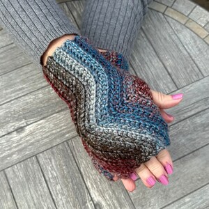 May include: A pair of fingerless gloves with a chevron pattern in shades of blue, brown, and red.
