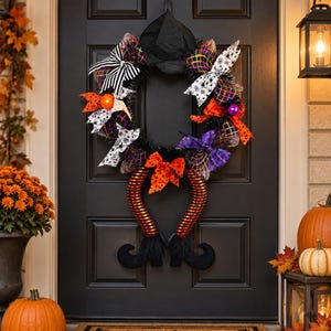 May include: A Halloween wreath featuring a black witch hat at the top, black tinsel, and decorative bows in black and white stripes, spider web patterns, and orange polka dots. Two striped orange and black legs with black boots hang downward.