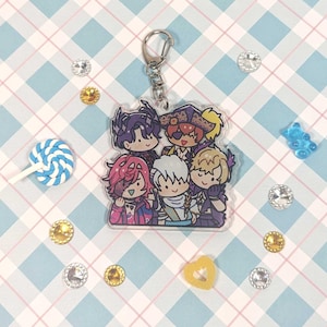 Peut inclure: Un porte-clés en acrylique transparent avec cinq personnages de dessin animé. Les personnages sont un garçon aux cheveux violets, un garçon aux cheveux roux avec un chapeau de pirate, un garçon blond avec un chapeau bleu, un garçon blond avec un chapeau bleu et une fille aux cheveux roses. Le porte-clés a un anneau en métal argenté.
