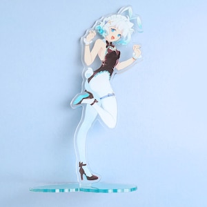 May include: A clear acrylic figure of an anime-style character in a bunny girl outfit. The figure has white hair with blue highlights, blue eyes, and is wearing a black and white outfit with high heels. The figure is standing on a clear base.