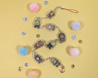 Könnte beinhalten: Ein transparenter Schlüsselanhänger mit einer silbernen Kette und Anhängern mit Comicfiguren aus dem Anime One Piece. Die Anhänger sind rund und zeigen verschiedene Charaktere aus der Serie, darunter Luffy, Zoro und Sanji. Der Schlüsselanhänger hat auch einen kleinen Ankeranhänger am Ende.