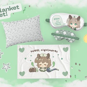 May include: A blanket set with a pillow, blanket, and two eye masks. The pillow has a repeating pattern of cartoon faces. The blanket features a cartoon character and the words "sweet nightmares". The eye masks have cartoon graphics.
