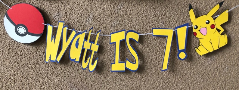 May include: A yellow and blue banner with the text "Wyatt is 7!" and a red and white Pokeball on the left and a yellow Pikachu character on the right.