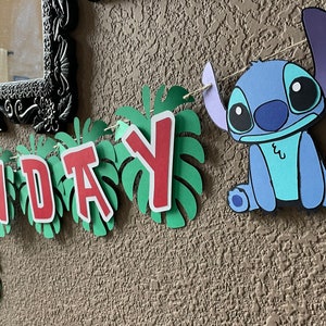 May include: A birthday banner with green leaves and red letters spelling "Birthday" and a blue Stitch character.