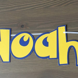May include: A yellow and blue banner with the name "Noah" in large letters. The banner also features a red and white Pokeball and a yellow Pikachu character.