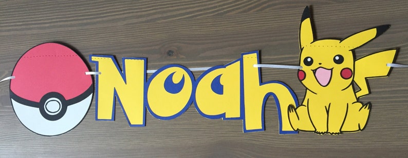 May include: A yellow and blue banner with the name "Noah" in large letters. The banner also features a red and white Pokeball and a yellow Pikachu character.