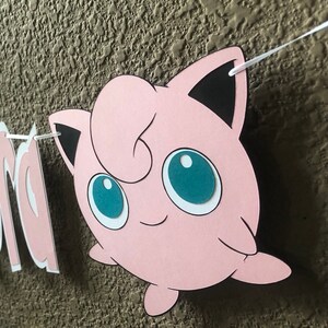May include: Pink and black paper cut-out of a cartoon character with large blue eyes. The character is a popular anime character.