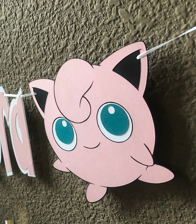 May include: Pink and black paper cut-out of a cartoon character with large blue eyes. The character is a popular anime character.