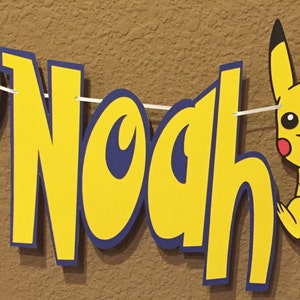 May include: A yellow and blue banner with the name "Noah" in large, bold letters. The banner also features a red and white Pokeball and a yellow Pikachu character.