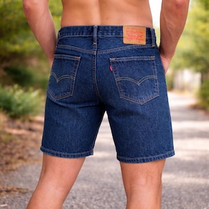 Könnte beinhalten: Dunkelblaue Jeansshorts mit klassischem Fünf-Taschen-Design. Mit rotem Levi's-Etikett hinten und kleinem rotem Etikett auf der Gesäßtasche. Die Shorts haben einen Knopf- und Reißverschluss und sind aus strapazierfähigem Denim.