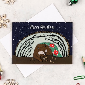 Bear hibernating Christmas card. Featuring an illustration of a bear hunkering down for winter in their cave