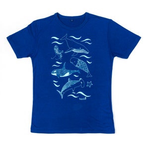 May include: A royal blue t-shirt with a white outline of various sea creatures, including a whale, a jellyfish, a shark, and a fish. The text "doodle" is printed in white at the bottom of the shirt.