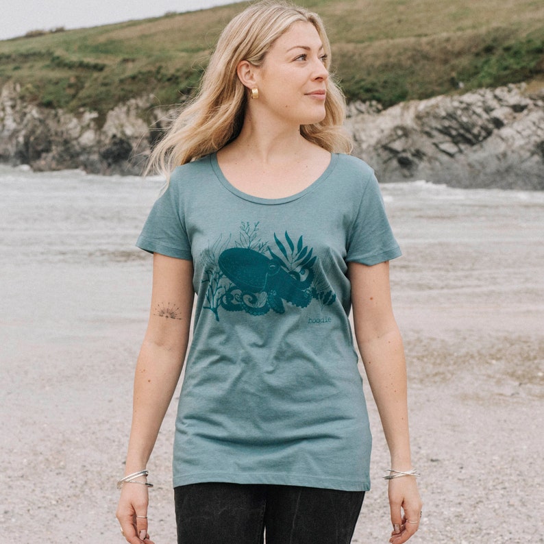 May include: A teal blue t-shirt with a dark blue octopus graphic and the word "doodle" printed on the bottom right corner.