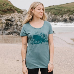 May include: A teal blue t-shirt with a graphic print of an octopus in a coral reef. The text "bookish" is printed on the bottom right of the design.