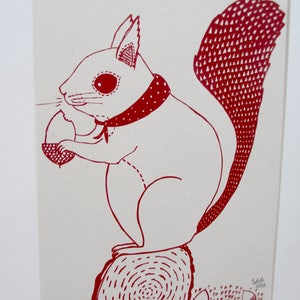 Puede incluir: Dibujo de l&iacute;nea roja de una ardilla con una bandana roja y sosteniendo una bellota. La ardilla est&aacute; sentada en un toc&oacute;n de &aacute;rbol con un patr&oacute;n de espiral rojo. Hay varias bellotas esparcidas alrededor del toc&oacute;n.