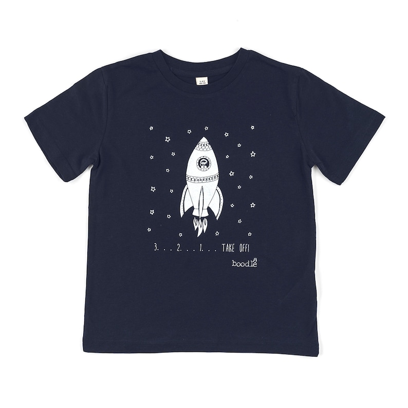 May include: A navy blue t-shirt with a white rocket ship design and the text "3...2...1... TAKE OFF! boodie" printed on the front.