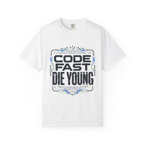 May include: A white short-sleeved t-shirt featuring a central graphic design with the text CODE FAST DIE YOUNG in a dark font. The text is surrounded by a blue and green circuit board pattern with various technical symbols and lines.