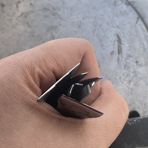 Puede incluir: Primer plano de una mano sosteniendo un juego de cuatro tenedores de plata. Los tenedores están apilados uno encima del otro, con los dientes de los tenedores apuntando hacia arriba.