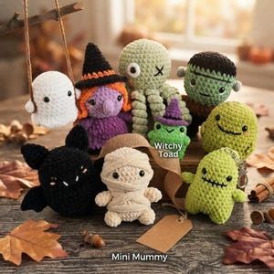 Può includere: Una collezione di piccole figure all'uncinetto che include un fantasma bianco, una strega viola con un cappello nero, un polpo verde, un mostro verde, un pipistrello nero, una mummia beige, una rana verde con un cappello viola e una creatura.