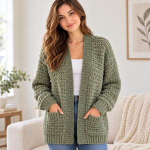 Peut inclure: Un gilet ouvert vert olive doté d'un motif en maille crochetée texturée, de manches longues avec poignets côtelés et de deux grandes poches plaquées à l'avant. Le vêtement est porté sur un haut blanc uni et un jean bleu.