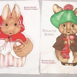 May include: Two fabric panels featuring Beatrix Potter Nursery Classics illustrations. Mrs. Bunny wears a red cape and holds a basket. Benjamin Bunny wears a green hat and brown jacket. Both panels have dotted outlines for cutting and stuffing.