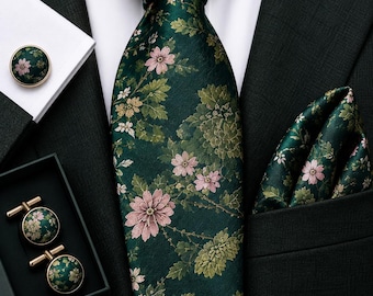 May include: A dark green necktie and matching pocket square featuring a floral pattern with pink flowers and green leaves. The set includes round cufflinks with the same floral design, all displayed against a black suit jacket and white shirt.
