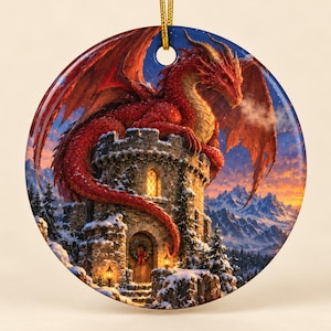 Op de afbeelding: Een rond keramisch ornament met een felrode draak die bovenop een stenen toren zit tijdens een besneeuwde winterzonsondergang. De toren heeft een verlicht raam en een deur versierd met een krans, tegen een achtergrond van bergen.
