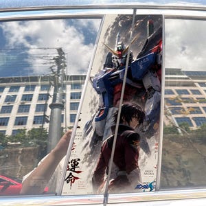 May include: A vertical car window decal featuring a large blue, white, and red Gundam robot standing behind a dark-haired character in a red uniform. The design includes Japanese text, the name Shinn Asuka, and the phrase I will make my own destiny.