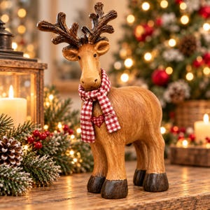 May include: A standing reindeer figurine with a light brown textured body, dark brown antlers, and dark brown hooves. The reindeer wears a red and white chequered scarf featuring a small red heart accent on the chest area of the fabric.