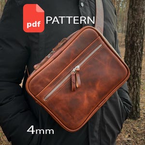Puede incluir: Un bolso bandolera de cuero marrón de forma rectangular, con un bolsillo frontal con cremallera y dos tiradores de cuero, una cremallera principal superior y una correa para el hombro. La imagen incluye un icono PDF rojo, el texto PATTERN y 4mm.