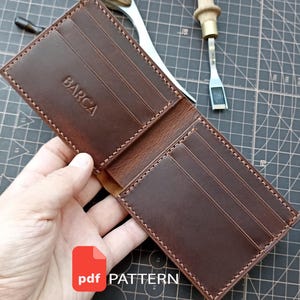 Pode incluir: Uma carteira de couro castanho tipo bifold com várias ranhuras para cartões e o texto BARCA em relevo. A carteira é apresentada ao lado de uma ferramenta de metal com cabo de madeira e uma ferramenta de corte, com um ícone vermelho pdf PATTERN.