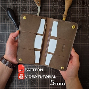 Op de afbeelding: Een bruine lederen bifold portemonnee met meerdere kaartsleuven, goudkleurige metalen drukknopen en de in reliëf aangebrachte tekst BARCA. Inclusief een PDF-patroon en video-tutorial, met een 5mm-maat aanduiding op het oppervlak.