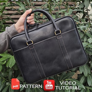 May include: A black leather briefcase featuring two top handles, a rectangular silhouette with rounded corners, and visible brown stitching along the handle attachments. The bag includes a PDF PATTERN and YouTube VIDEO TUTORIAL label.
