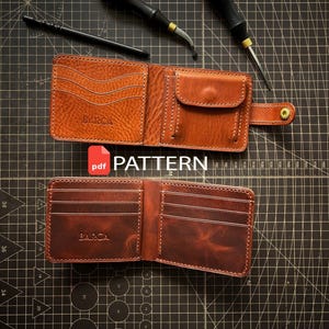 Puede incluir: Dos carteras de cuero abiertas con costuras visibles y ranuras para tarjetas. La cartera superior tiene un bolsillo para monedas con cierre a presión y la palabra BARCA grabada. La cartera inferior también muestra la palabra BARCA. Se incluyen dos herramientas.