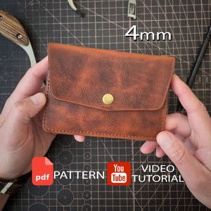 May include: A brown leather wallet with a textured finish, a flap closure, and a single brass-colored metal snap button. The wallet features visible stitching along the edges. The text 4mm, PDF PATTERN, and YouTube VIDEO TUTORIAL are present.