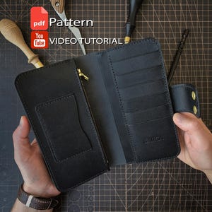 Può includere: Un portafoglio lungo in pelle nera con tasca con cerniera, scomparti per carte e chiusura a scatto. L'interno presenta il marchio BARCA impresso. Il portafoglio è mostrato con strumenti e il testo PDF Pattern e VIDEO TUTORIAL.