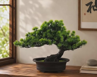 May include: A small artificial bonsai tree with vibrant green needle-like foliage and a textured dark brown trunk. The tree is planted in a shallow, matte black oval ceramic pot with a wide rim and a stable base, creating a balanced appearance.