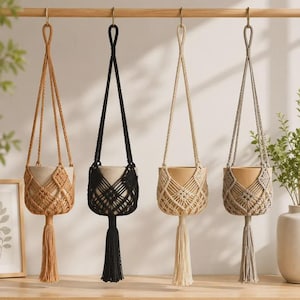 May include: Four macrame plant hangers suspended from a wooden rod. Each hanger features a knotted cord design in a different color: mustard yellow, black, cream, and grey. Each includes a central pot holder and a long decorative tassel at the base.
