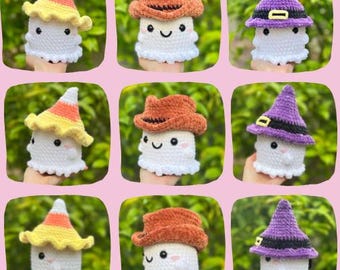 May include: A collection of nine crocheted ghost figures featuring three distinct designs: a ghost wearing a yellow and orange candy corn hat, a ghost with a brown cowboy hat, and a ghost sporting a purple witch hat with a black band and buckle.