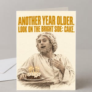 May include: A greetings card featuring a sepia-toned illustration of a person with curly hair and a beard. The text reads: ANOTHER YEAR OLDER. LOOK ON THE BRIGHT SIDE: CAKE. A small cake with four lit candles sits on a table in front of the person.