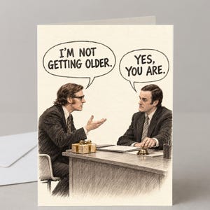 May include: A greeting card featuring a sketch of two men in suits sitting at a desk. One man gestures while saying, I'M NOT GETTING OLDER. The other man replies, YES, YOU ARE. A small gift box and a desk bell sit on the table between them.