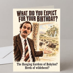 May include: A greeting card featuring a man in a brown suit and striped tie gesturing toward a window. The text reads: What did you expect for your birthday? The Hanging Gardens of Babylon? Herds of wildebeest? The illustration shows a stampede.