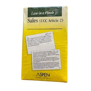 Puede incluir: Un juego de tarjetas de estudio rectangular Law in a Flash Sales (UCC Article 2) envuelto en plástico transparente. La cubierta es amarilla con un encabezado verde oscuro, con texto sobre Wile E. Coyote y principios legales. Aspen Publishers está impreso en la parte inferior.