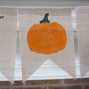 May include: A burlap banner with the word "Happy" and a pumpkin design. The banner is strung together with twine.