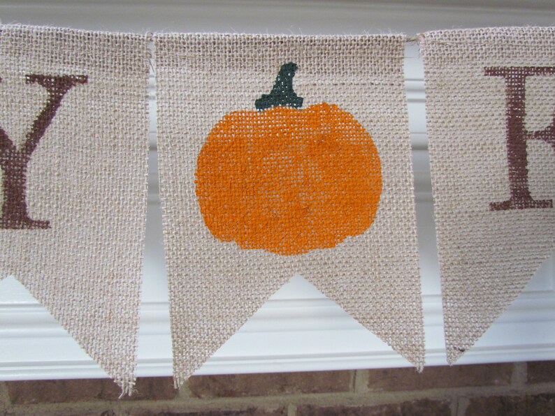 May include: A burlap banner with the word "Happy" and a pumpkin design. The banner is strung together with twine.