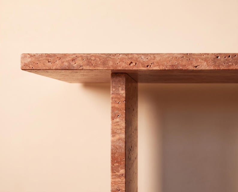 May include: A table constructed from reddish-brown travertine stone featuring a flat rectangular top surface supported by a single vertical slab leg. The natural stone material displays a porous, textured surface with visible pits and variations.